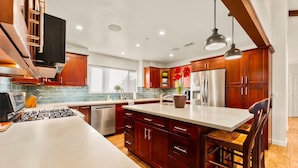 A modern kitchen with wooden cabinets, a central island, stainless steel appliances, and pendant lighting. - 25% Off Sept WkDay Great 4 Families, Walk 2 Beach! (Ventura)