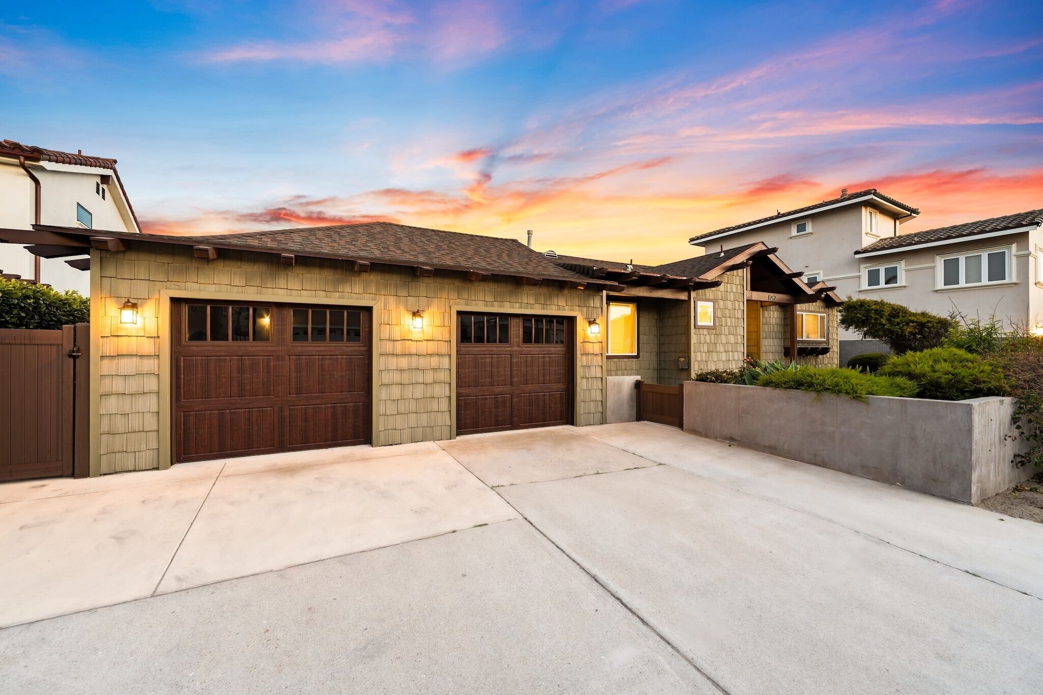 Une maison d’habitation avec un garage, une allée et une pelouse bien entretenue.