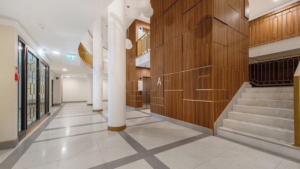 En rymlig korridor med en central trappa, träpanel och en modern design.