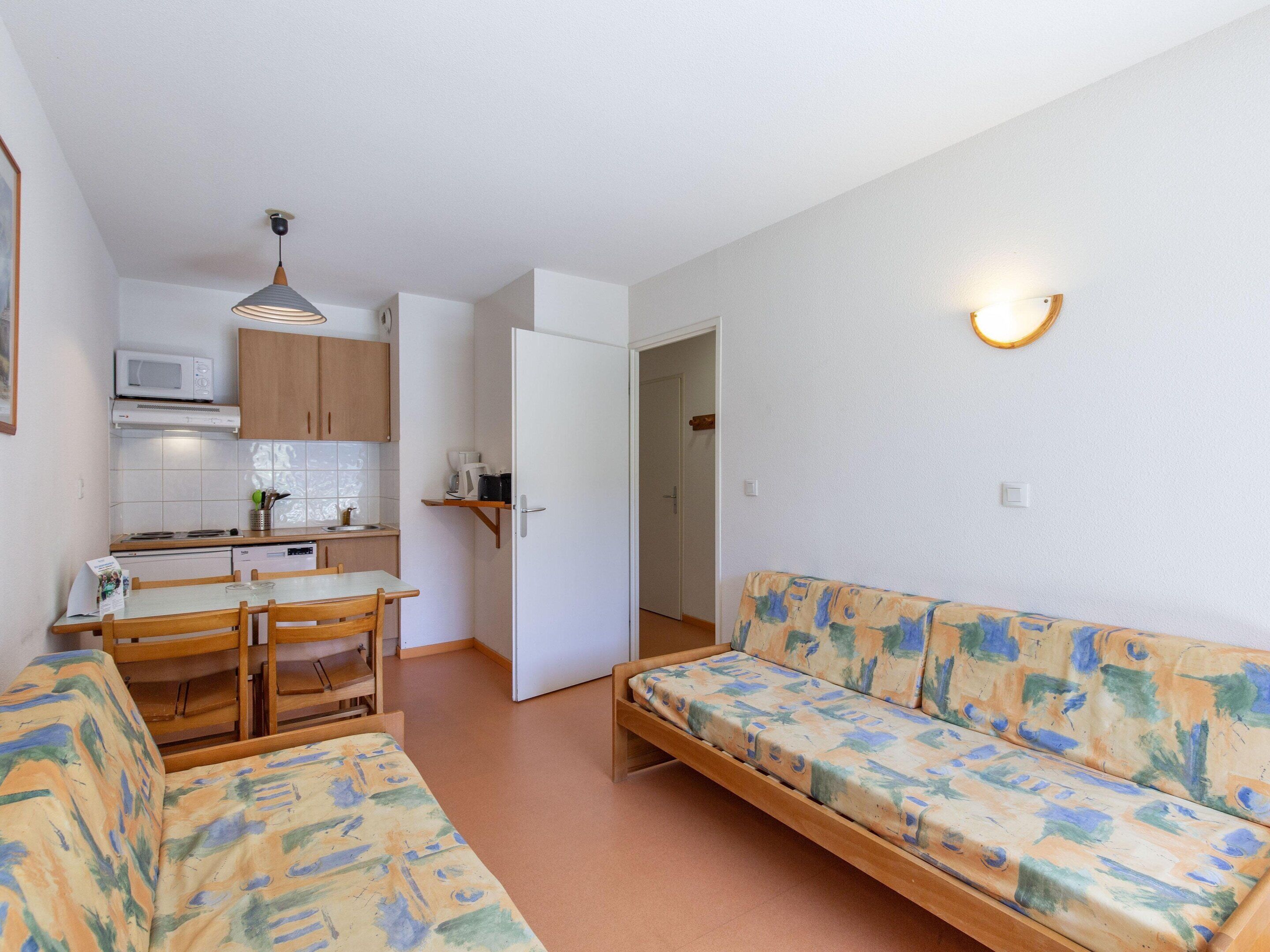 A compact living space with a kitchenette, a dining area, and a sofa.