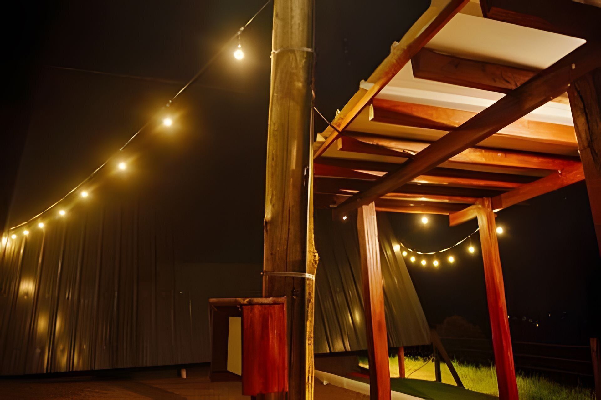 Una estructura de pérgola de madera al aire libre con luces colgantes.