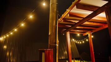 Una estructura de pérgola de madera al aire libre con luces colgantes.