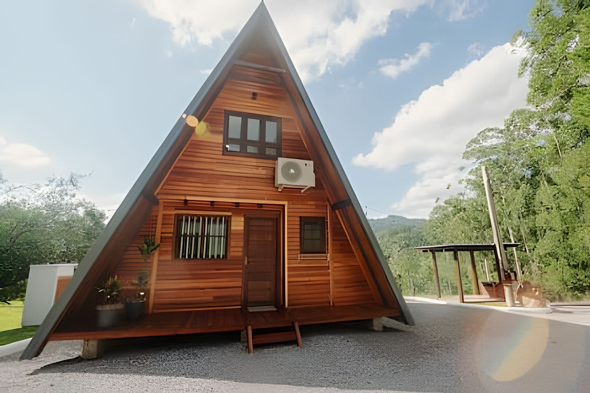Ein hölzernes, dreieckiges Haus mit Tür, Fenstern und einer Klimaanlage.