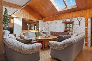 A cozy room with wooden walls, a high ceiling, and a skylight. There is a round wooden table with chairs and a Christmas tree. - Guesthouse “Goéland Room” with Shared Terrace, Garden and Wi-Fi (Gerbépal)