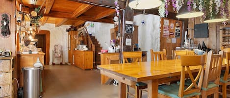 A rustic wooden interior with a dining table, chairs, and a kitchen area.