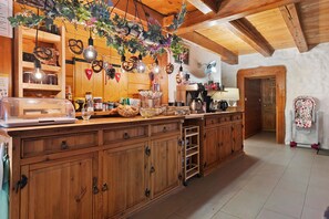 Una cocina rústica con armarios de madera, una isla central, adornos colgantes y diverso menaje de cocina.