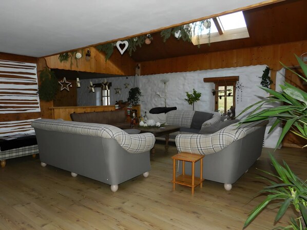 A cozy living room with a sofa set, a wooden coffee table, and a small wooden stool.