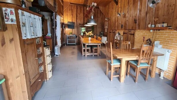 Een houten interieur met een eettafel en stoelen, een radiator en een rood gordijn.