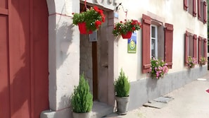 A building with red shutters, potted plants, and a visible door.