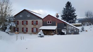 A two-story house with a snow-covered roof and a visible chimney.