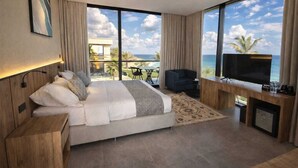 Una habitación de hotel moderna con una cama grande, un escritorio, un televisor y vistas al océano.