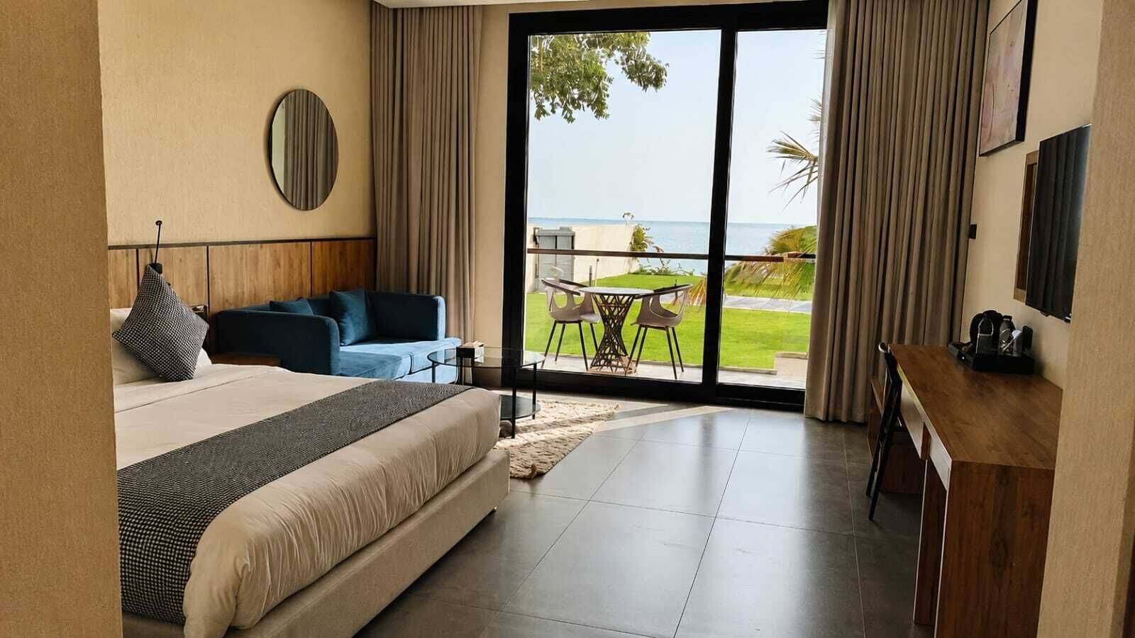 Een slaapkamer met een bed, een bank, een eettafel en uitzicht op de oceaan.