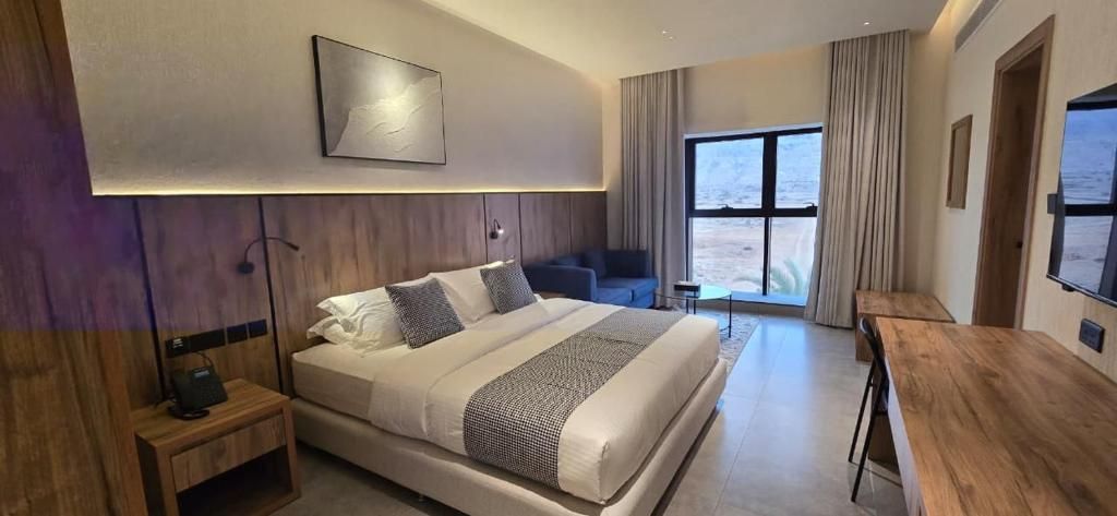 Una habitación de hotel moderna con una cama grande, un escritorio y vistas a la playa.