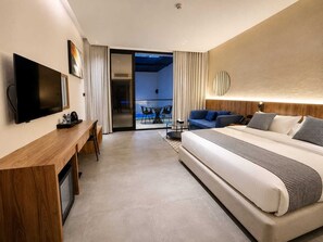 A modern hotel room with a large bed, a desk with a flat-screen TV, a balcony with a view, and a well-lit ceiling. - Dhabab Bay Resort (Bimmah)