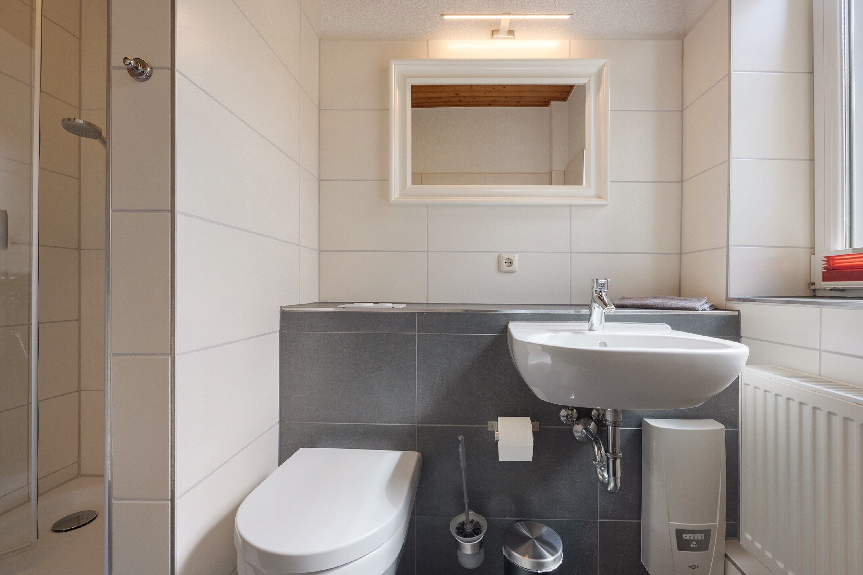 A modern bathroom with a toilet, sink, and shower.
