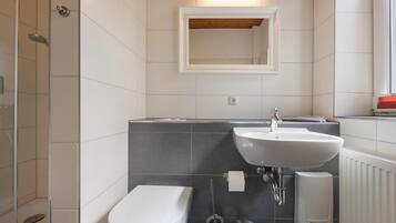 A modern bathroom with a toilet, sink, and shower.