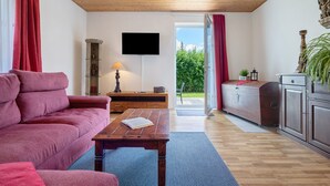 A living room with a sofa, a coffee table, a TV, and a sliding door leading to an outdoor area. - Holiday Apartment for 6 People (83 m²) in Redefin (Redefin)