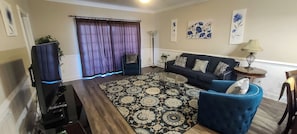 A living room with a sofa, armchair, coffee table, and a TV stand.
