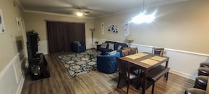 A living room with a dining table, blue sofa, and a patterned rug.