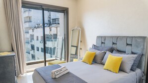 Une chambre d’hôtel avec un grand lit, un miroir et une vue sur les immeubles par la fenêtre.