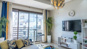 Un salon moderne avec un canapé, un téléviseur et une vue sur le balcon.