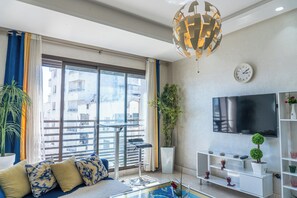 Ein modernes Wohnzimmer mit Sofa, Fernseher und Balkonblick.