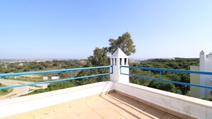 Une terrasse sur le toit offrant une vue dégagée sur le paysage environnant, une petite structure blanche et des rampes bleues.
