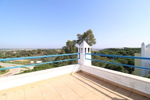 A rooftop terrace with a clear view of the surrounding landscape, a small white structure, and blue railings. - Real Village (Faro)