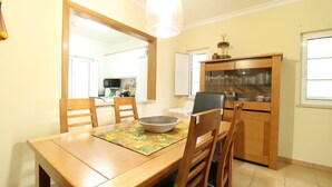 Un coin repas comprenant une table en bois, des chaises, un saladier et un buffet contenant de la verrerie.