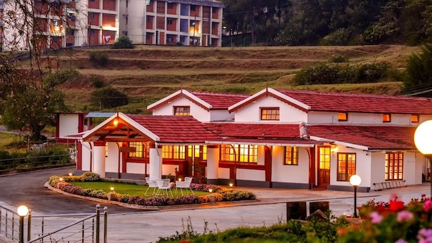 Un hotel con tejado de tejas rojas, varias ventanas y una entrada bien iluminada.