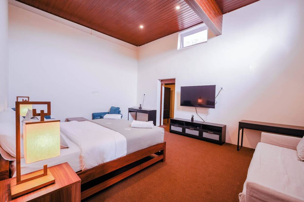 A hotel room with two beds, a TV, a desk, and a window.