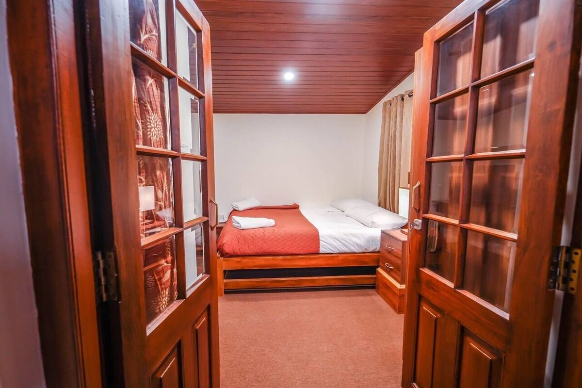 A bedroom with a bed, wooden wardrobe, and a door with glass panels.