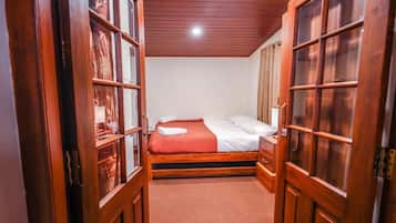 A bedroom with a bed, wooden wardrobe, and a door with glass panels.