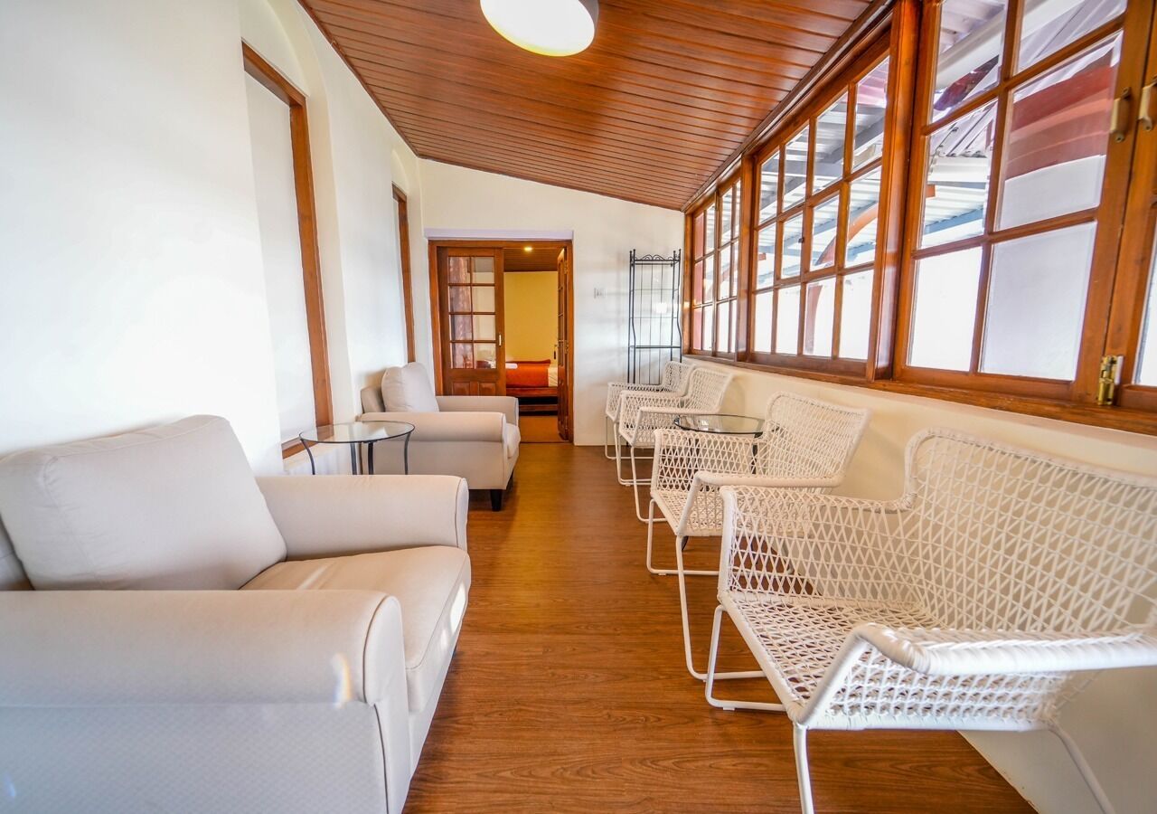 Ein Zimmer mit Holzbalkendecke, weißen Sofas und Korbstühlen.