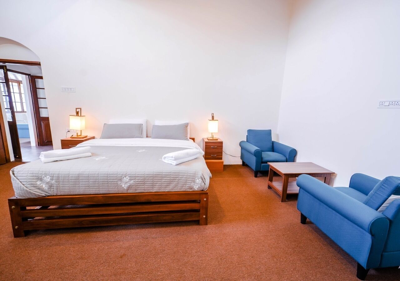 Een slaapkamer met een bed, twee nachtkastjes, een blauwe bank, een kleine tafel en een wandlamp.