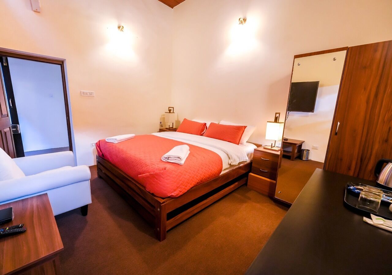 A hotel room with a bed, a desk, a chair, a mirror, and a wardrobe.
