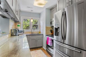 Eine moderne Küche mit Edelstahlgeräten, einem Fenster mit Blick auf Grünflächen und einer Arbeitsplatte mit einem Toaster.