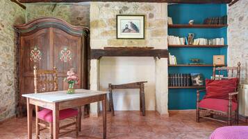 Una habitación con una mesa de madera, una silla, una estantería y una chimenea.