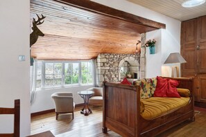Una habitación acogedora con una cama de madera, una chimenea de piedra, techo de madera y una decoración con cabeza de venado.