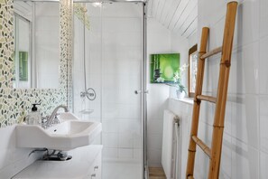 A bathroom with a shower, sink, and a wooden ladder.