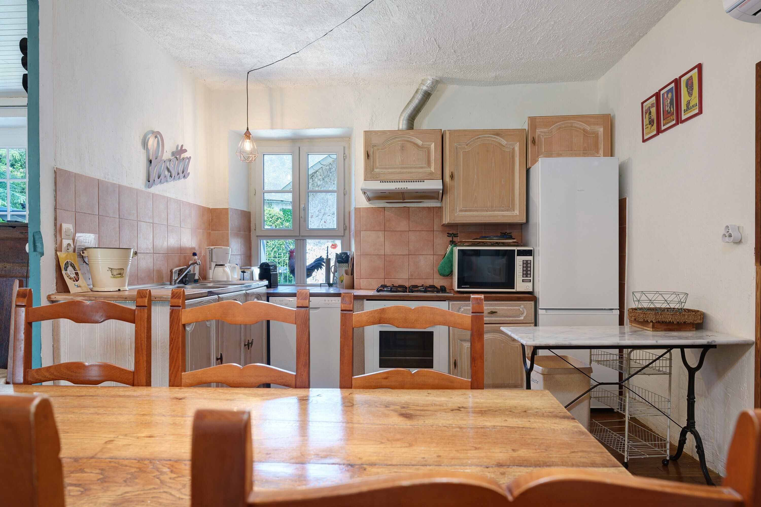 A kitchen with wooden cabinets, a white refrigerator, and a dining table with chairs.