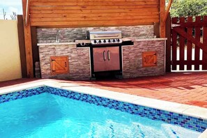 A pool with a barbecue area, stone walls, and a wooden fence. - This cozy 3BD villa is located only 8 minutes from Eagle, Arashi and Palm Beaches<br>- your own private pool <br>- total privacy with an 8 feet wall fence around the property<br>- huge 40 square meters covered outdoor living area<br>- BBQ and outdoor (Noord)