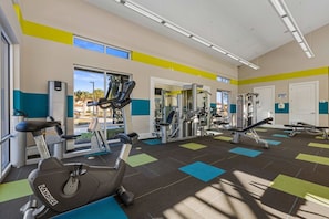 Une salle de sport équipée de divers appareils d’exercice, notamment un tapis de course, des appareils de musculation et un banc de développé couché.
