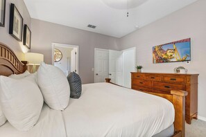 Une chambre à coucher avec un lit, une commode, un miroir et une porte.