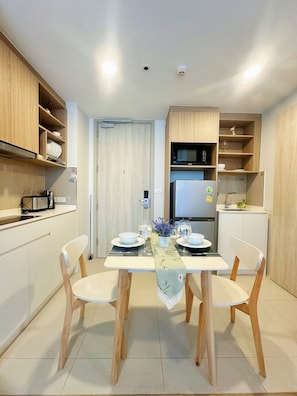 Eine moderne Küche mit Holzschränken, einem Esstisch für zwei Personen und einem Kühlschrank.