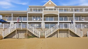 Ein mehrstöckiges Strandhotel mit Balkonen, ein Sandstrand davor und ein klarer Himmel.