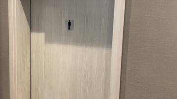 Uma porta de madeira com uma placa acima indicando 'Herren' e o símbolo de banheiro masculino na porta.