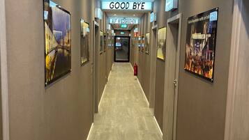 A hotel hallway with a 'GOOD BYE' sign, 'AUF WIEDERSEHEN' sign, and a 'Was' sign.