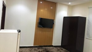 Una habitación con puerta de madera, televisor de pantalla plana montado, armario y suelo alfombrado.