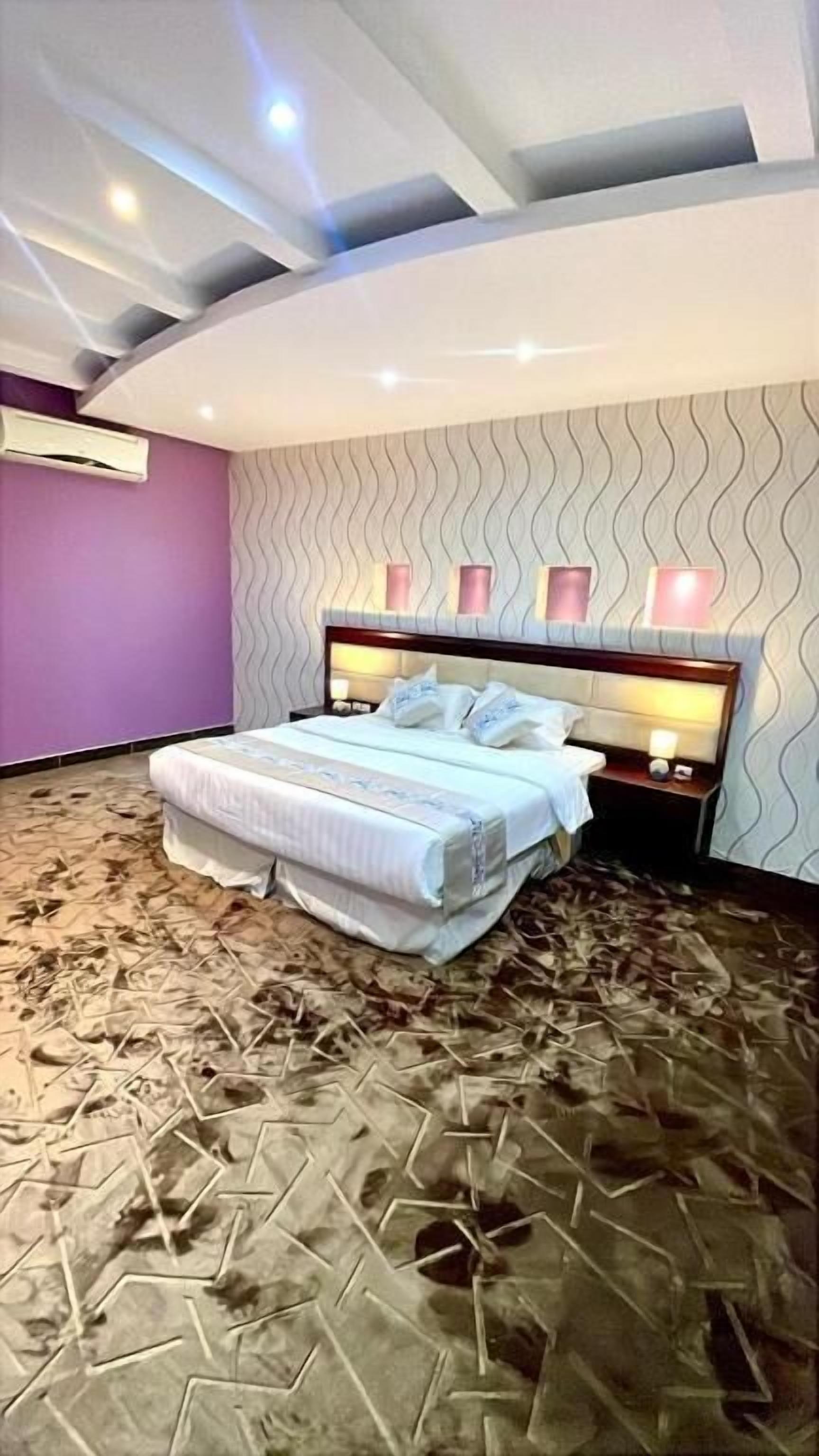Ein Schlafzimmer mit einem Bett, einem Nachttisch, einer Wand-Klimaanlage und einem gemusterten Teppich.